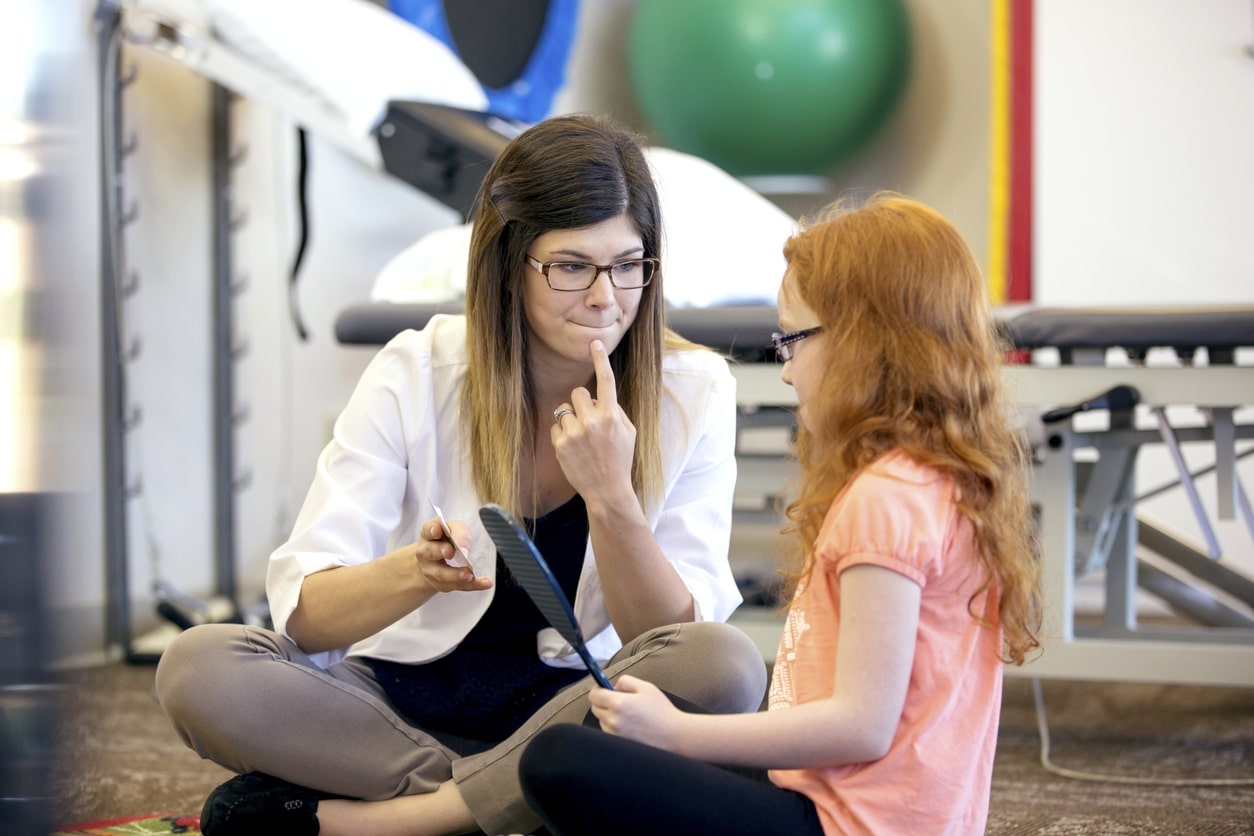 Female speech therapist practicing Auditory Verbal Therapy with young patient.